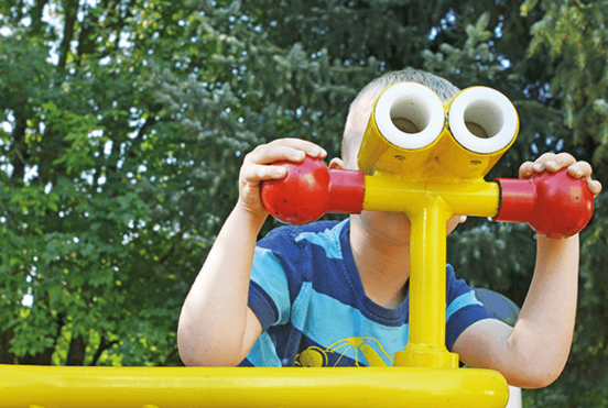 Ein Junge schaut im Kindergarten durch ein Fernrohr.