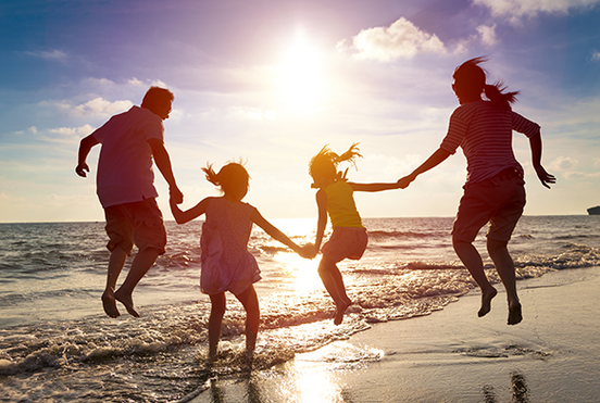 Familie mit zwei Kindern spielen am Strand.