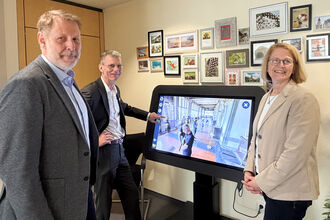 Zwei Männer und eine Frau stehen neben dem CareTable