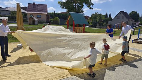 Kinder und Erwachsene enthüllen ein Außenspielgerät