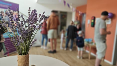 Stehtisch mit Lavendelstrauß und Besucher in der Kita Blankenburg unscharf im Hintergrund