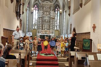 Kita-Kinder mit Pfarrer und Erziehern bei einer Aufführung in der Kirche vor Publikum