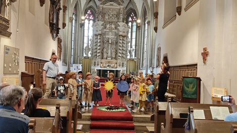 Kita-Kinder mit Pfarrer und Erziehern bei einer Aufführung in der Kirche vor Publikum